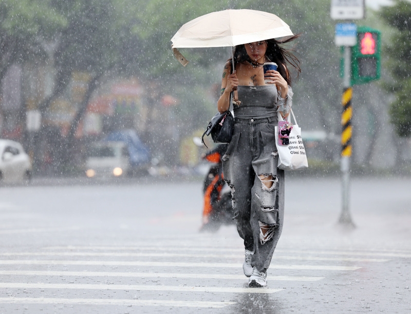 民眾撐傘遮擋雨勢。 （中央社記者張新偉攝）