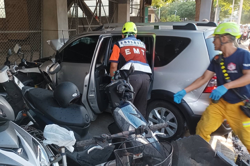 一輛銀色自小客車12日下午疑似由成功大學成功校區內高速開出校門，在大學路與一輛自小客車碰撞後撞進騎樓，一路波及多輛機車，其中1名女性機車騎士當場死亡。圖為消防人員趕抵救援。（圖為讀者提供，中央社記者楊思瑞台南傳真）