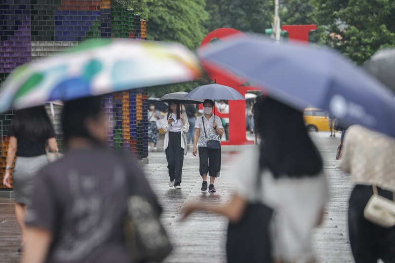 民眾雨後撐傘。（中央社記者裴禛攝）