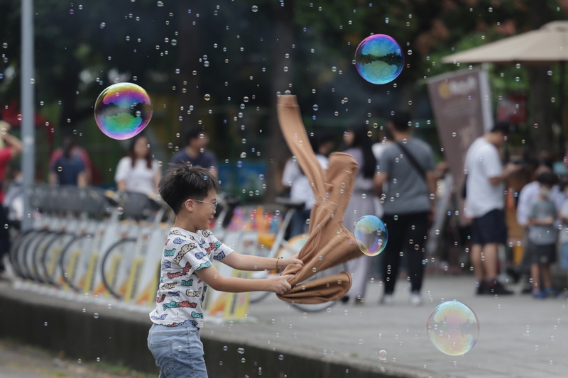 小朋友在公園追著泡泡玩耍，享受假期好天氣。 (中央社記者裴禛攝）