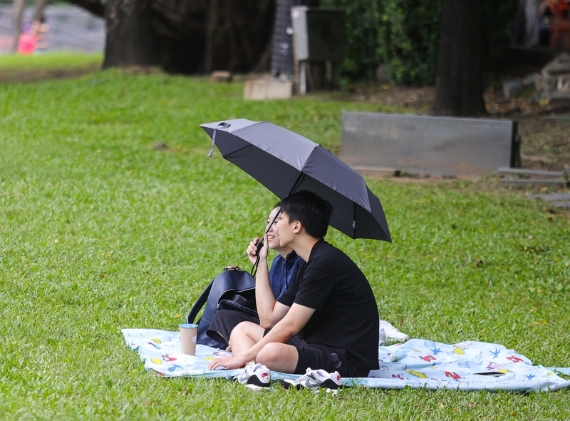 民眾出外踏青，在華山大草原綠地撐傘休憩。（ 中央社記者謝佳璋攝）