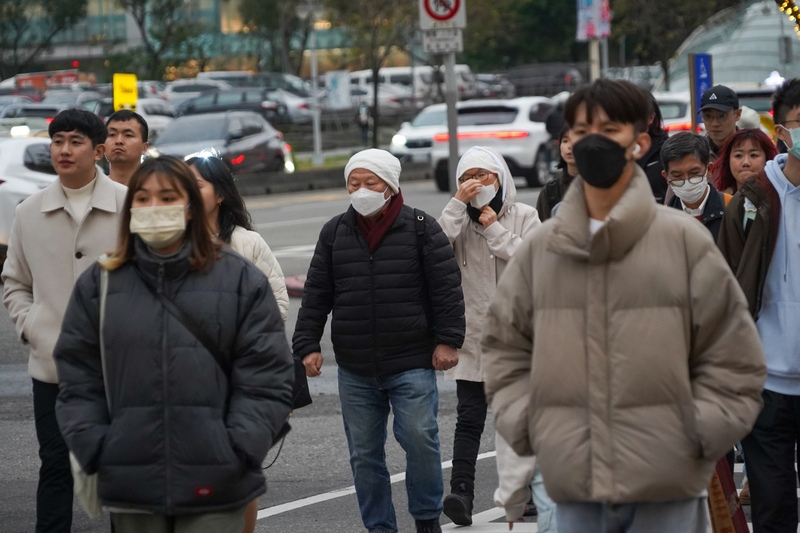 圖為台北市信義區街頭滿是穿著厚外套、戴口罩防寒的民眾。( 中央社記者裴禛攝）